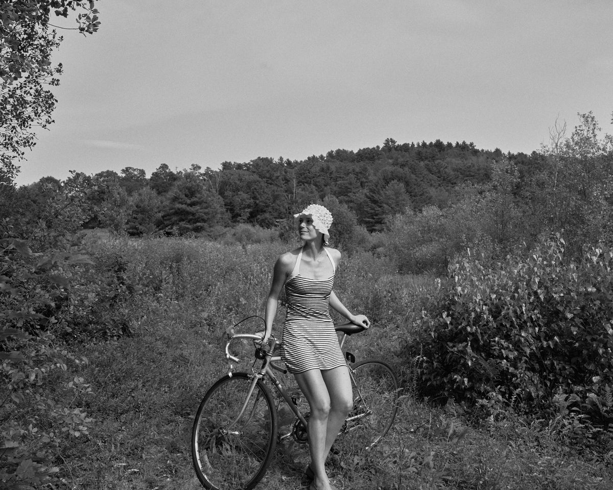 Woman riding a bike wearing Dena full coverage A-line swim skirt and Tzofia halter top in scalloped stripe